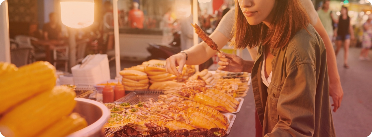 Une femme se tenant devant un buffet rempli de nourriture, préparé par un traiteur barbecue.